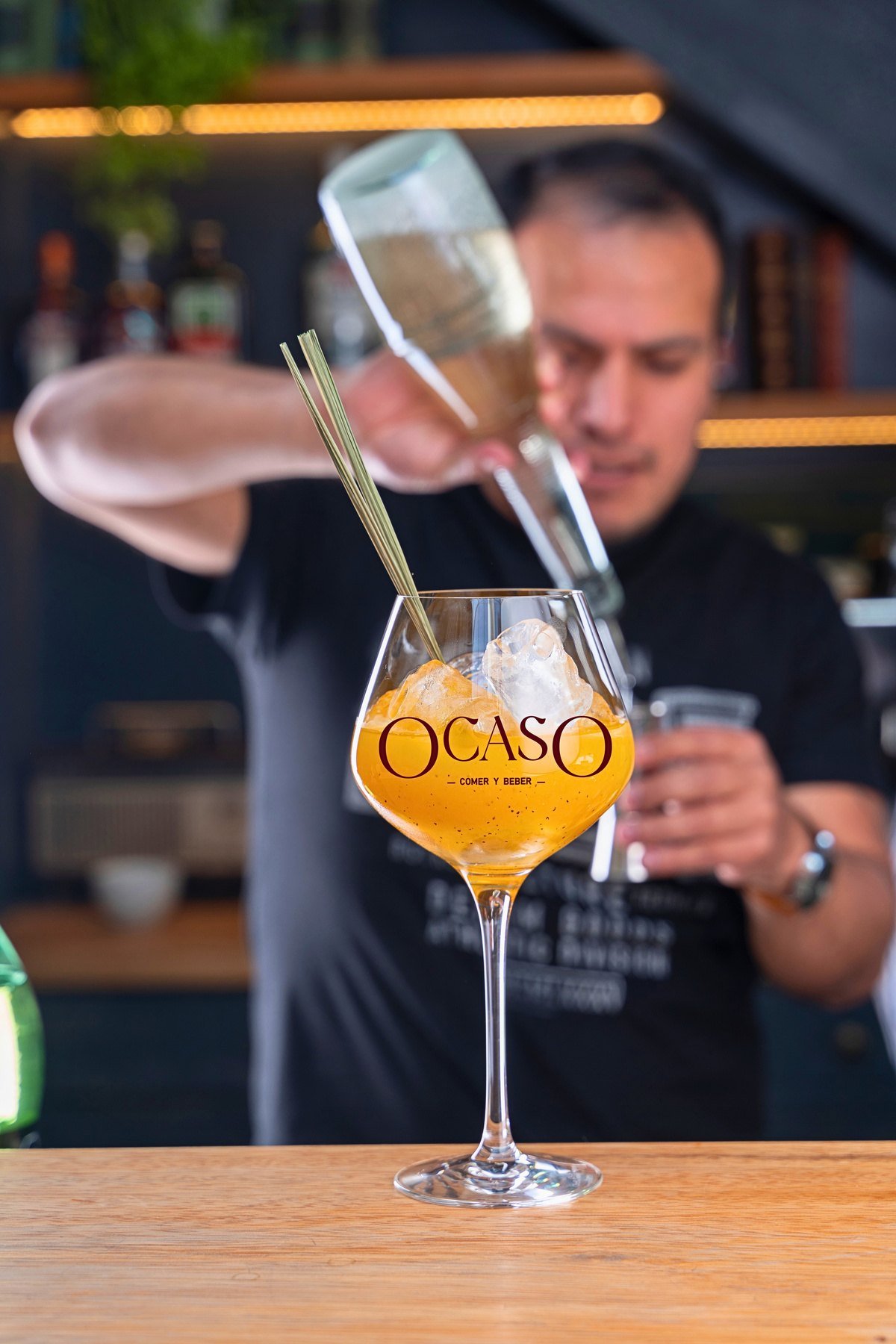Bartender preparando un trago Ocaso en copa de gin.